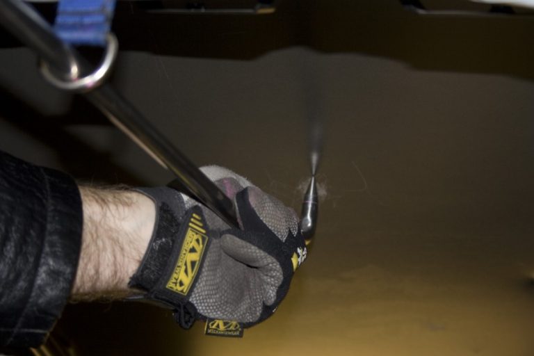 A gloved hand steadying a long tool